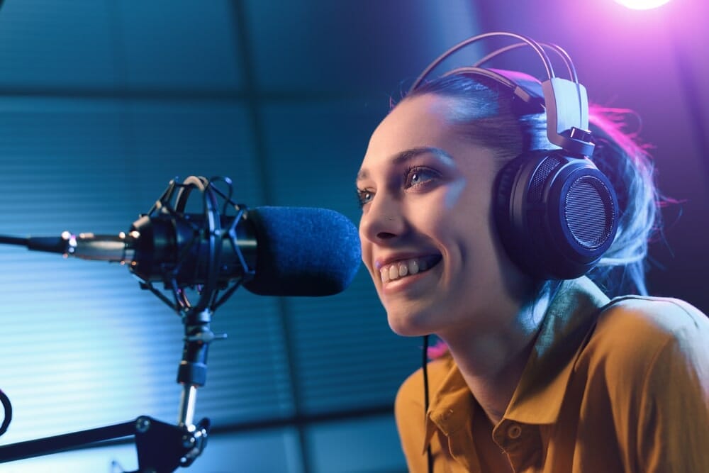 Young,Smiling,Woman,Wearing,Headphones,And,Talking,Into,A,Microphone